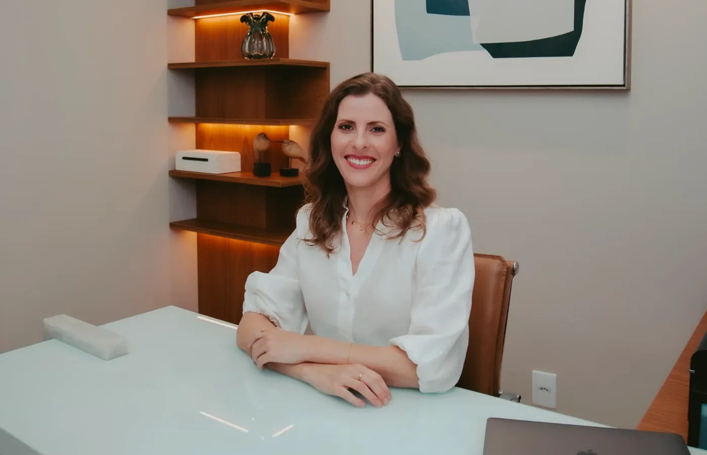 Dra. Milena Hungria à mesa do consultório, onde acontece a conversa da consulta